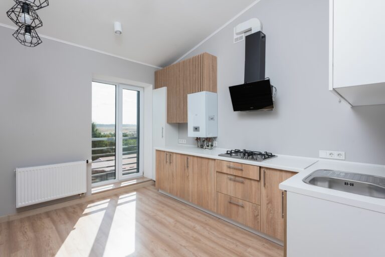 MöbelTech - Nowoczesne meble na wymiar Stylish empty kitchen with wooden cabinets and large windows.